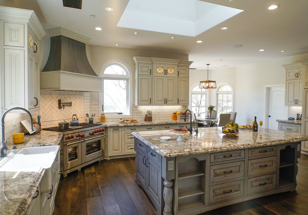 Spacious modern kitchen with cream cabinetry, granite countertops, island, and professional stove
